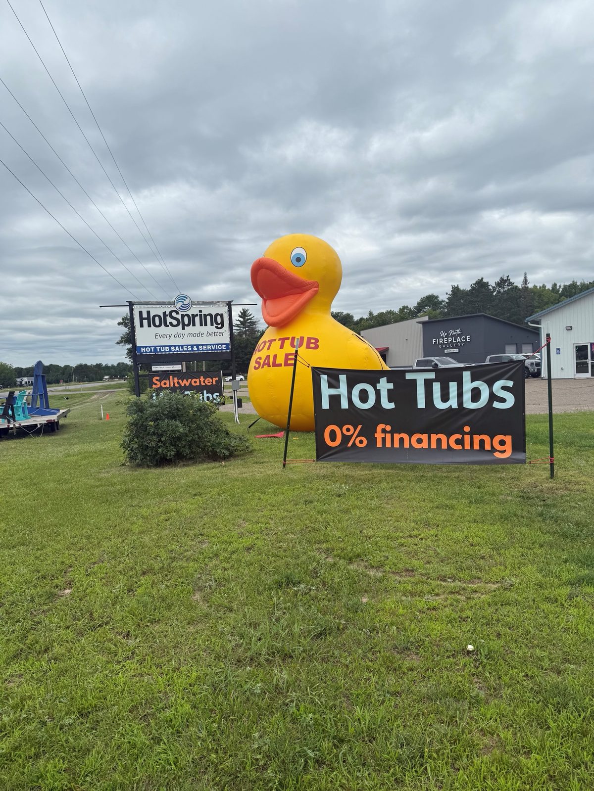 Giant inflatable duck with Hot Tub Sale printed on it beside a roadside sign