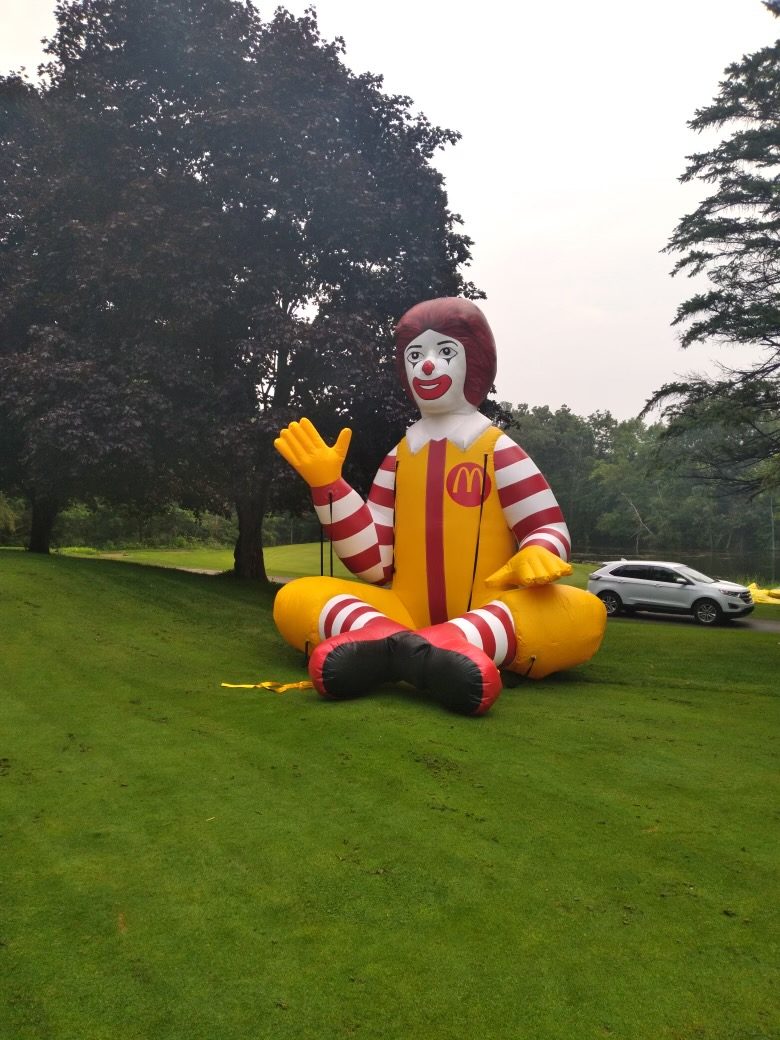15 ft inflatable Ronald McDonald seated on a golf course at an event
